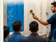 Trainer demonstrating coating application tools to a group of workers