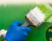 Gloved hand applying protective coating to a wall with a brush